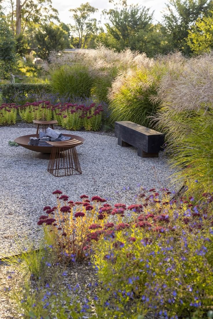 Jardín diseñado con gramíneas, canteros florales, sendero de gravilla y fogonero