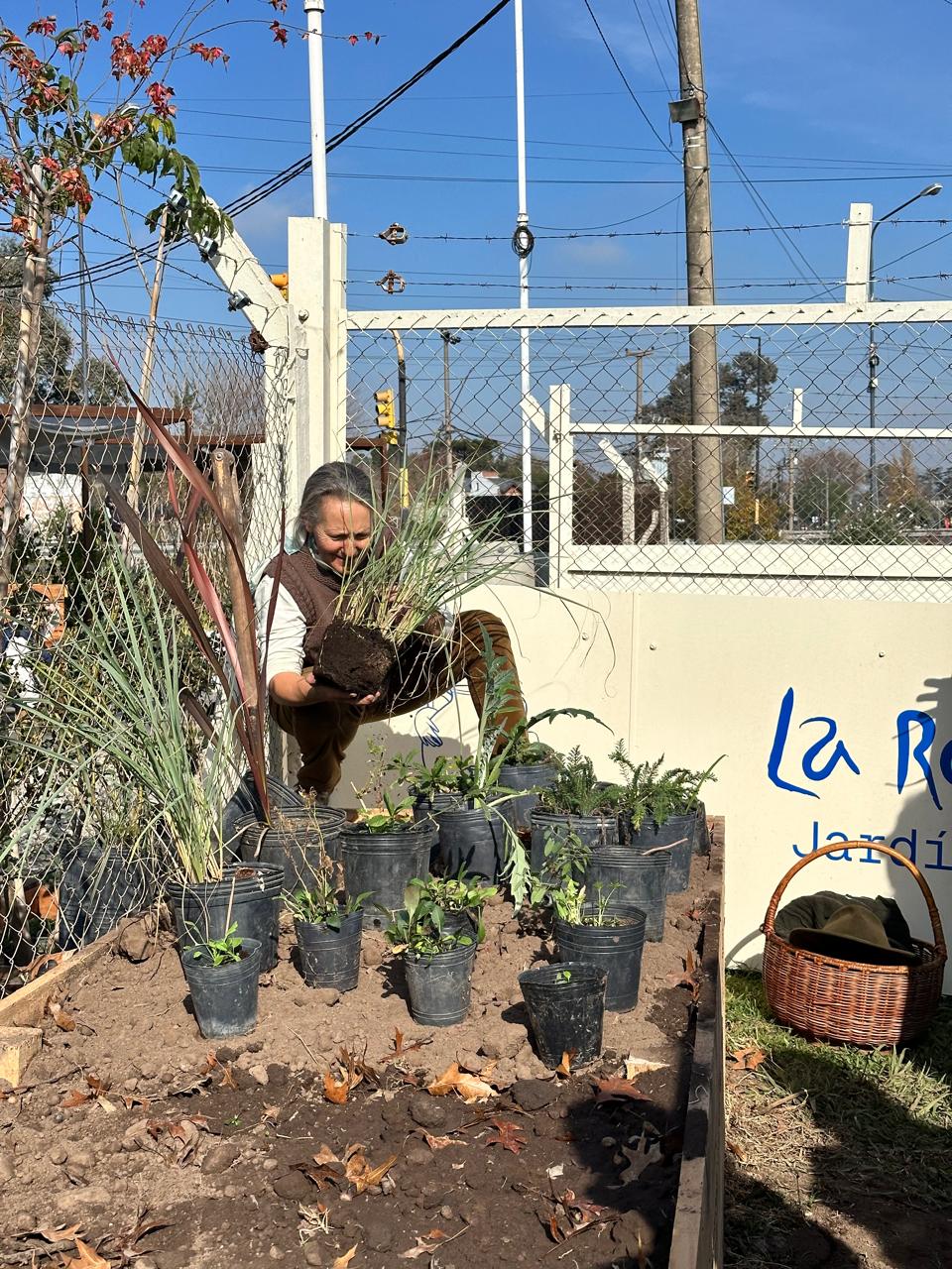 Tallerista plantando junto al cartel de La Romería