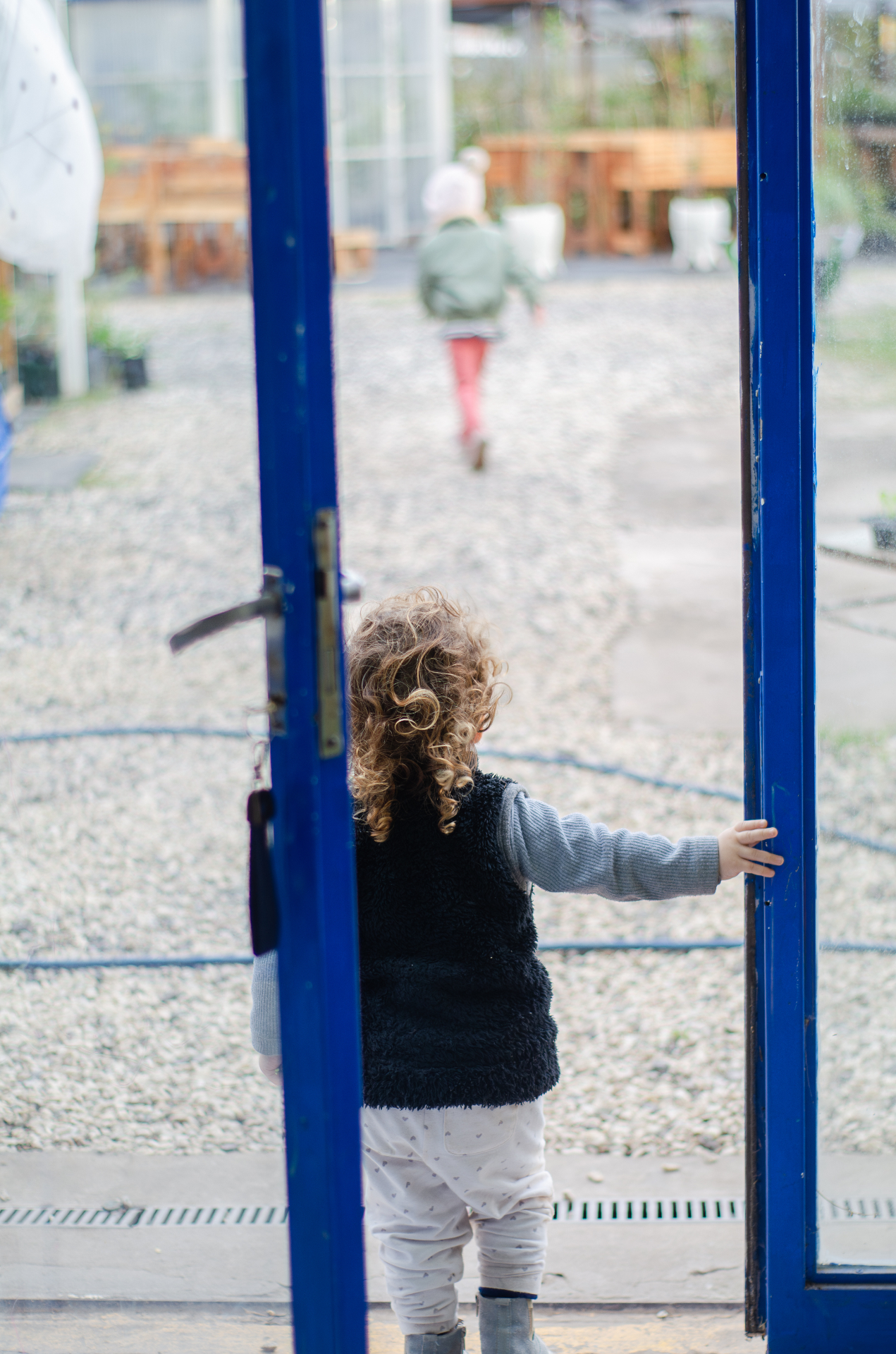 Niña abriendo la puerta azul hacia el exterior de La Romería