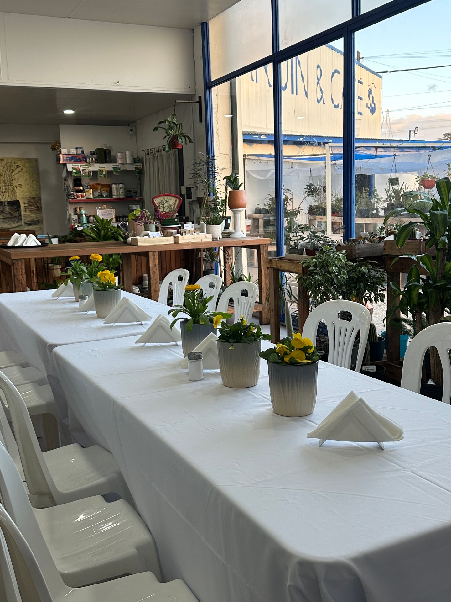 Espacio de eventos en La Romería: mesa larga decorada con flores amarillas, luz natural y el jardín de fondo